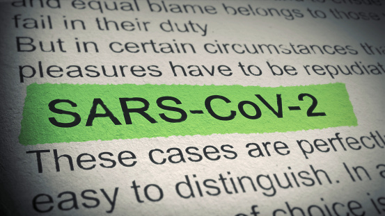 A closeup shot of a newspaper article with the word SARS-CoV-2 highlighted in green