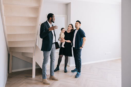 Real estate agent giving room tour for young Multi-racial family