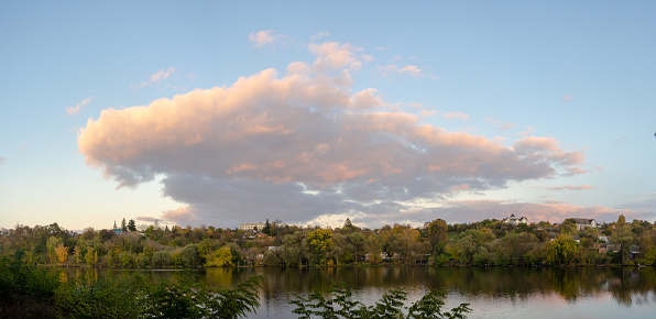 A calm lake surrounded by autumn trees at sunset