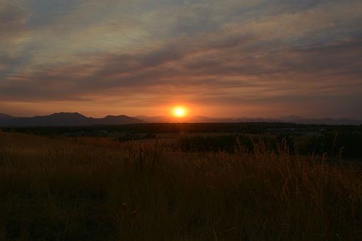 A mesmerizing sunset over the field with mountains in the background in Boulder, Colorado