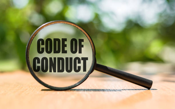 Magnifying glass with text CODE OF CONDUCT on wooden table and green background. Magnifying glass with text CODE OF CONDUCT on wooden table and green background. musical conductor stock pictures, royalty-free photos & images