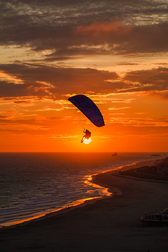 The silhouette of a person paragliding at sunset. Zoutelande, Zeeland, the Netherlands.