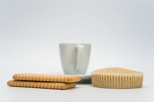 black hot ristretto coffe in a white stoneware cup with plate and pastries on a white surface with text space