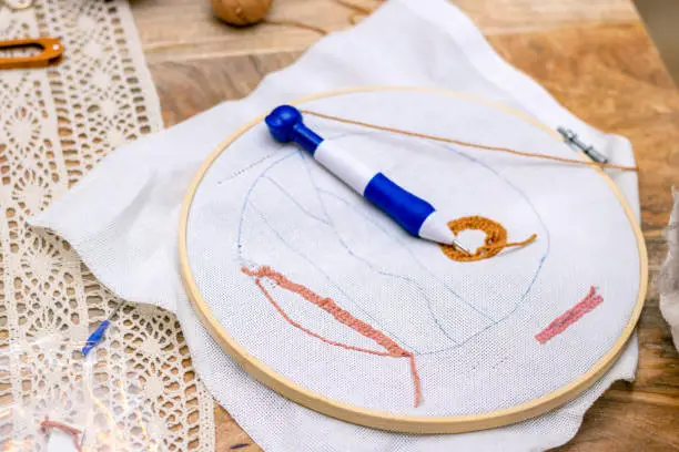 Embroidery punch needle workshop. Close-up of the hoop with the embroiderer in the middle.