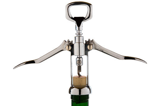 A closeup shot of a metal corkscrew opens a wine bottle isolated on a white background