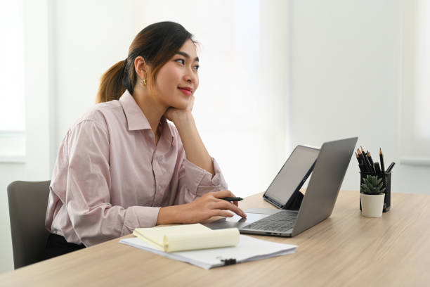 istock Beautiful female employee using laptop computer and doing some paperwork at her workstation. 1461014417