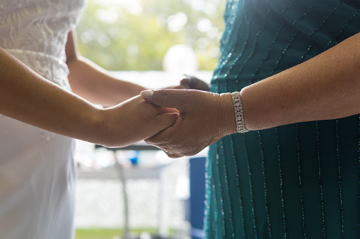 The mother of the bride holding the hands of the bride before the wedding ceremony