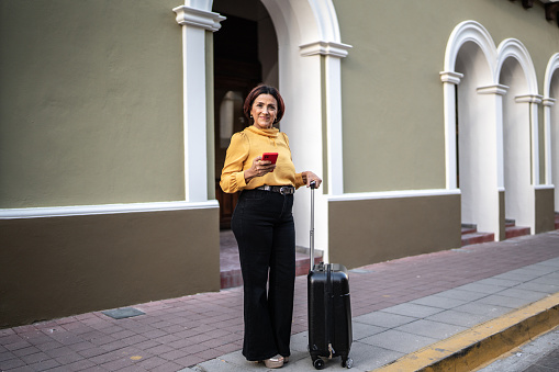 Portrait of senior woman carrying luggage at the historic district
