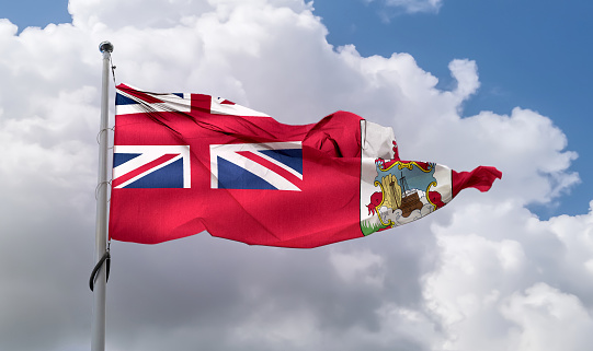 A Bermudan flag waving on a pole in a blue sky