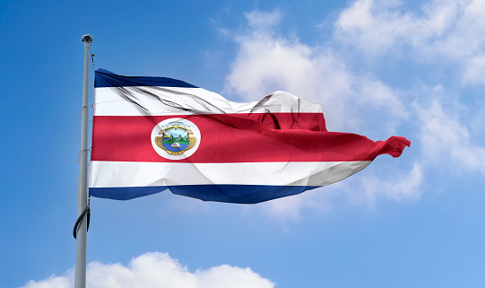 A Costa Rica flag waving on a pole in a blue sky