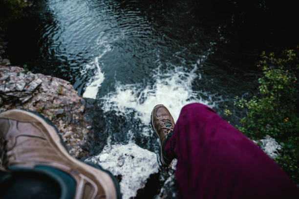 A male's feet on the rocks above a waterfall