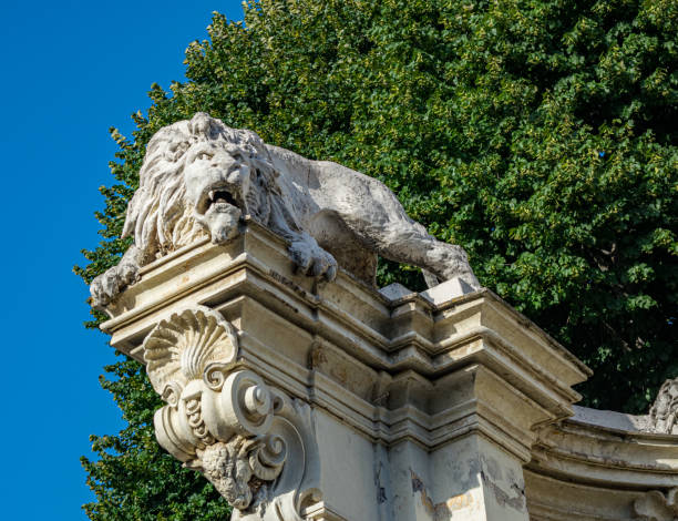 istock Statue of a lion with a thickly growing tree in the background on a sunny day 1461020609
