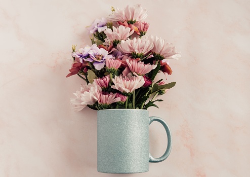 A closeup shot of beautiful flowers in a cup pot on the pink background