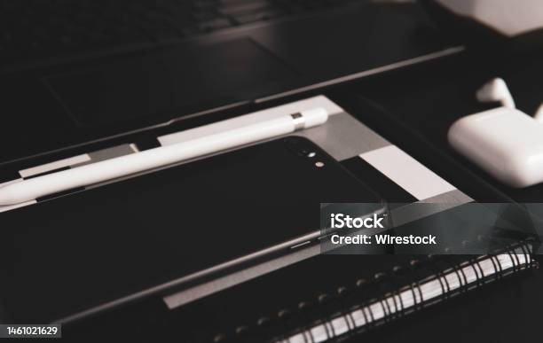 Closeup Shot Of A Smartphone Laptop And Wireless Earphones On The Table In Grayscale Stock Photo - Download Image Now