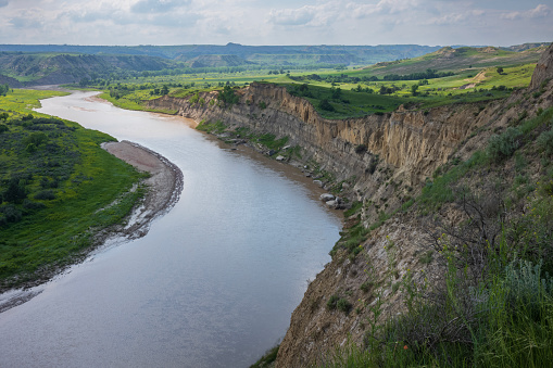 Theodore Roosevelt National Park of North Dakota, shown here during a summer day with cumulus clouds in the sky, is where the Great Plains meet the rugged Badlands. The Little Missouri River flowing.