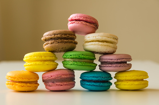 The colorful macarons stacked in a pyramid form on a white table