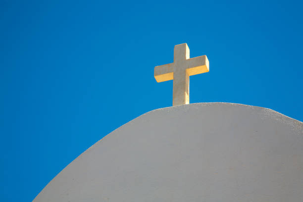 A low angle view of a white cross on an arc white building against a blue cloudy sky