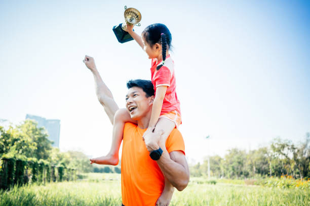 Father and daughter celebrating with trophy in hands