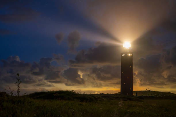 istock Lighthouse in the dunes with lightbeams at night 1461034738