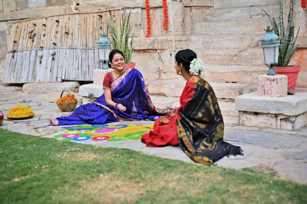 Two beautiful Indian women in saris talking to each other while filling Rangoli colours in a Palace in Rajasthan