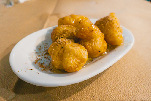 Loukoumades are little bite-sized golden puffs of fried dough that are sprinkled with sweet syrup, walnuts and cinnamon. With crispy outside and fluffy inside this Greek donut will give you absolute deliciousness.