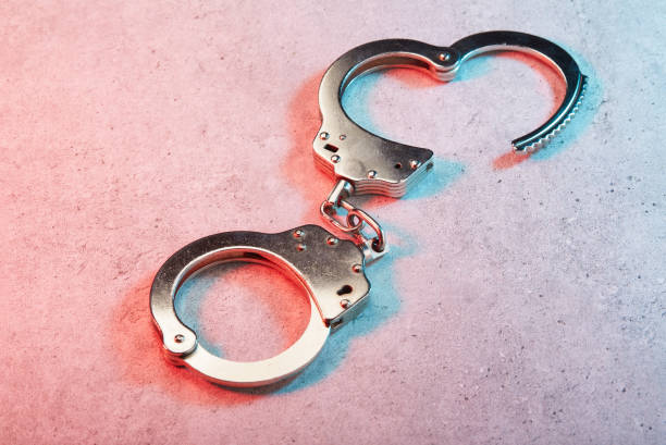 istock Handcuffs on concrete surface under colorful police lights 1461040888