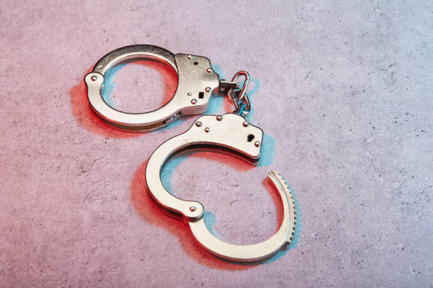 istock Handcuffs on concrete surface under colorful police lights 1461041098
