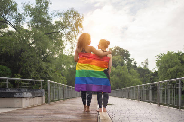 Portrait of fit healthy multi ethnic couple of women, people with LGBT rainbow flag, doing exercise, working out, and training in public garden park and recreation.Lifestyle activity with nature trees retrato de una pareja multiétnica de mujeres saludables y en forma, personas con bandera arcoíris lgbt, haciendo ejercicio, haciendo ejercicio y entrenando en el jardín público y el parque y la recreación. actividad de estilo de vida con árboles natu