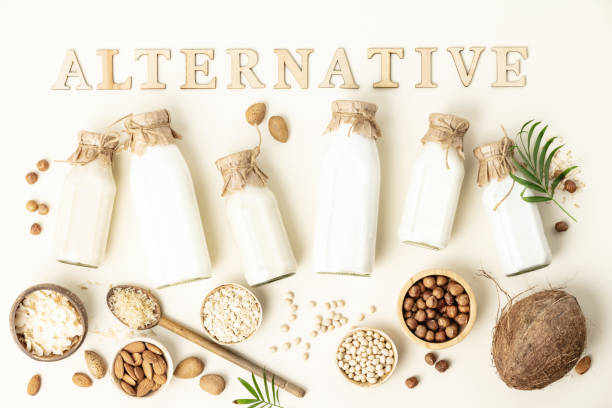 Non dairy plant based milk in bottles and ingredients on light background with wood letters. Alternative lactose free milk substitute, flat lay stock photo