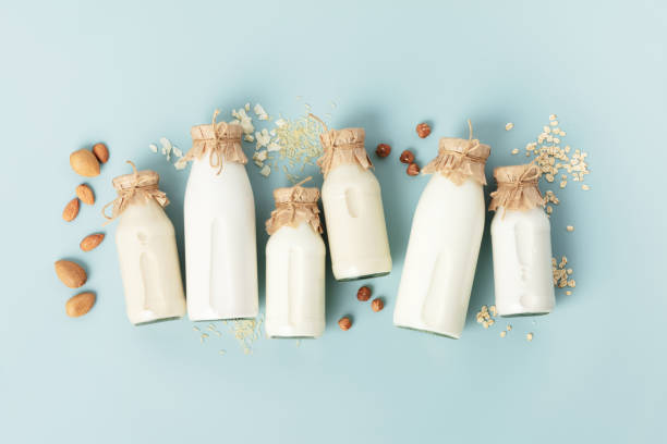 on dairy plant based milk in bottles and ingredients on turquoise background. Alternative lactose free milk substitute, flat lay stock photo