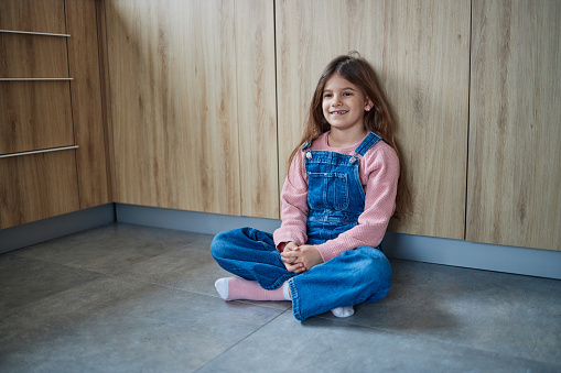 Portrait of a beautiful girl sitting in the kitchen floor, relaxing.