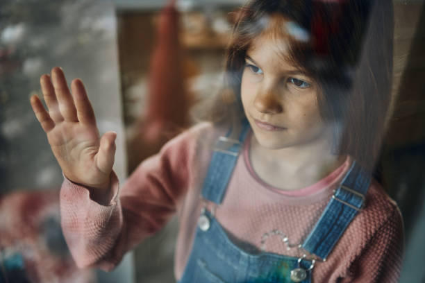 istock Beautiful sad girl looking through window 1461044471