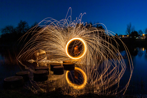 Light painting with steel wool; Pyrotechnic display at night with a reflection in the water.