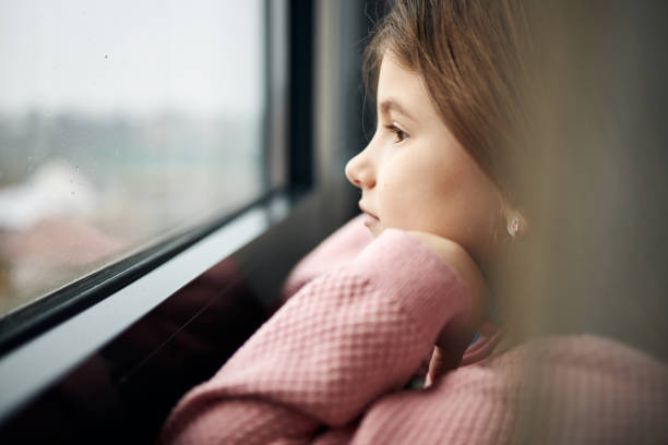 istock Beautiful sad girl looking through window 1461044937