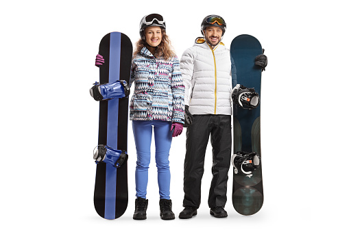 Full length portrait of a young man and woman posing with snowboarding equipment isolated on white background
