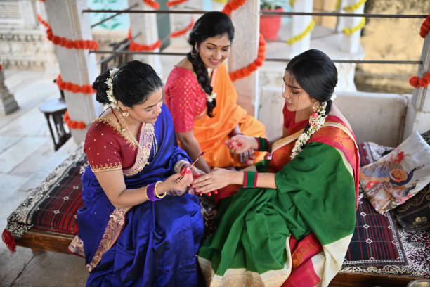 istock Indian Woman in sari applying Alta (red dye) on other woman's hand during a traditional function 1461049370