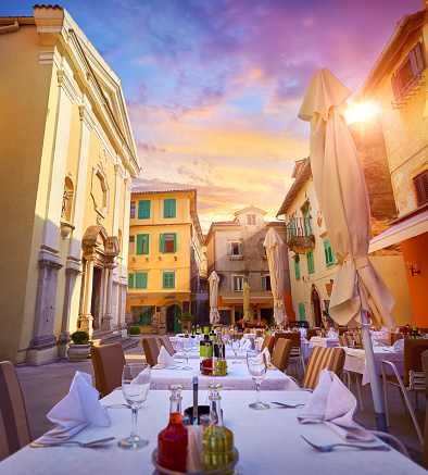 Lovran, Croatia. Central area of ancient old town with vintage buildings and cosy street cafes restaurants. Sunny summer evening sunset. Urban landscape historical centre