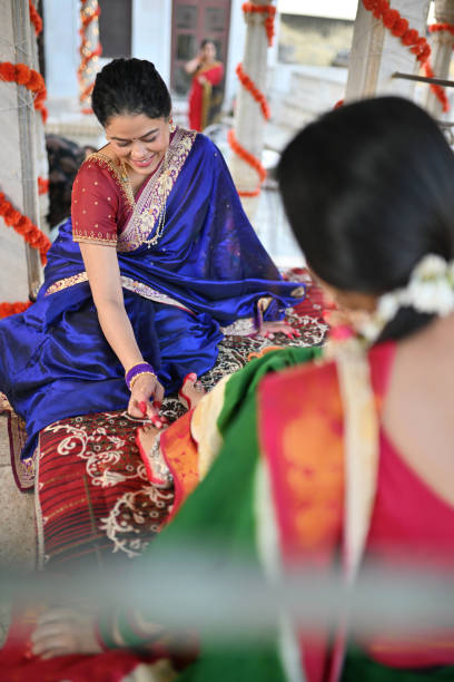 istock Woman in sari applying Alta (red dye) on other woman's feet during a traditional function 1461051326