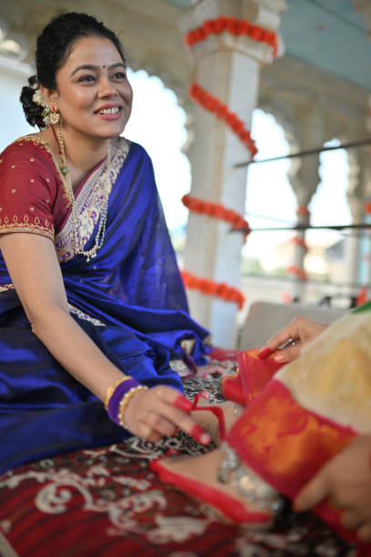 istock Woman in sari applying Alta (red dye) on other woman's leg during a traditional function 1461051377