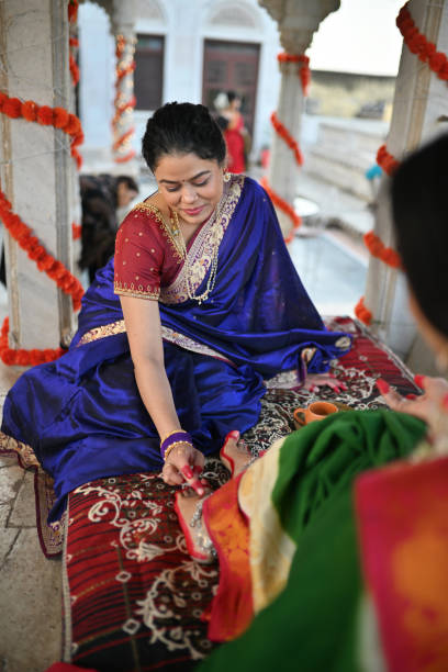 istock Woman in sari applying Alta (red dye) on other woman's feet during a traditional function 1461051495