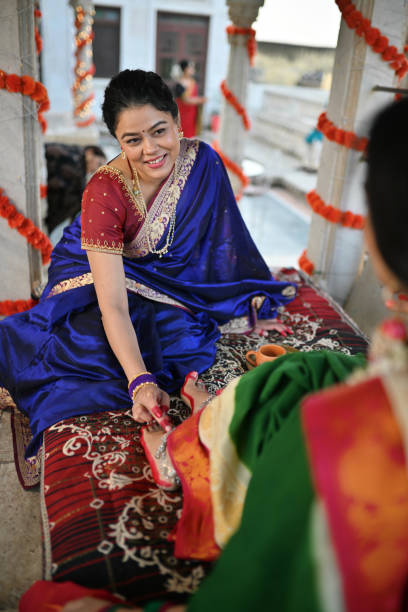 istock Woman in sari applying Alta (red dye) on other woman's feet during a traditional function 1461051498