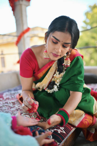 istock Woman in sari applying Alta (red dye) on her daughter's hand during a traditional function 1461051813