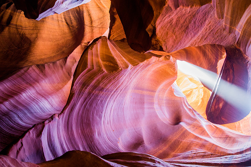Colorful formations in Upper Antelope Canyon. Rock texture with pink, magenta and orange colors. Light showing off the glamorous detail of the ancient spiral rock arches.