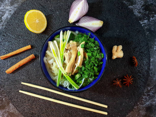 Traditional Pho Bo soup with beef, rice noodles, ginger, lemon in a bowl on a dark background. Vietnamese and Asian cuisine.