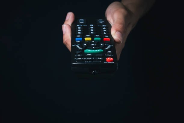 istock Woman holding TV remote control in the dark 1461067265