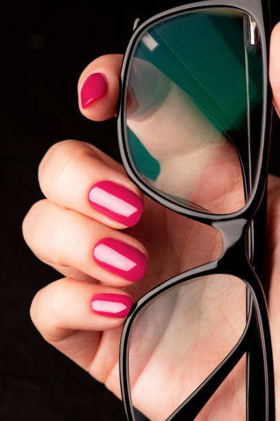 istock Hand with viva magenta, pink nails and glasses 1461067562
