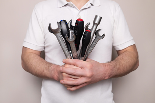 Man with bouquet of wrenches, spanners and screwdrivers