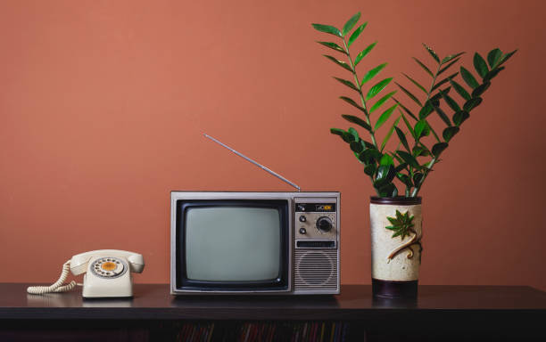 televisor antiguo vintage con teléfono giratorio anticuado y jarrón sobre mesa de madera en la sala de estar con fondo de pared de hormigón. - telephone old old fashioned desk fotografías e imágenes de stock