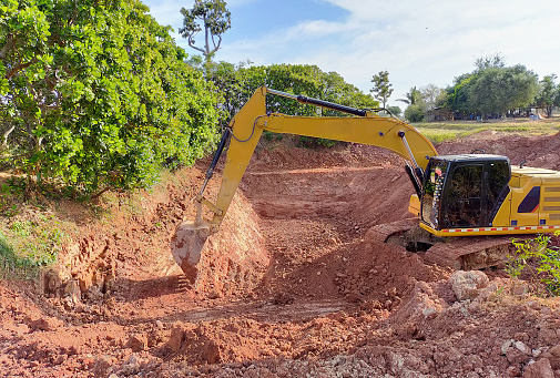 Backhoe bucket digging the soil at agriculture farm to make pond. Crawler excavator digging at shale layer. Excavating machine. Earth moving equipment. Excavation vehicle. Construction business.