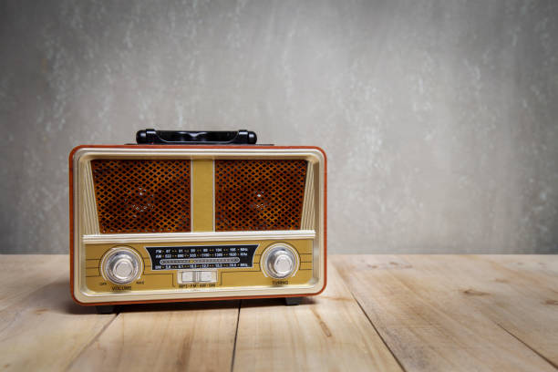 istock Retro broadcast radio receiver on wooden table front concrete wall background. 1461069329